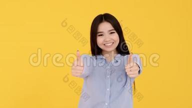 开朗的亚洲女孩穿着蓝色衬衫显示班级两只手在黄色背景上。
